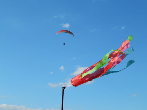 Параплан в небі та кольоровий вітровказівник на стартовому майданчику Дністровського каньйону