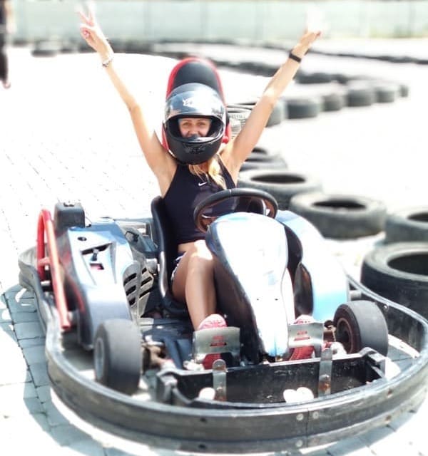Дівчина сидить у карті з піднятими руками під час заїзду картингу на треку в Івано-Франківську