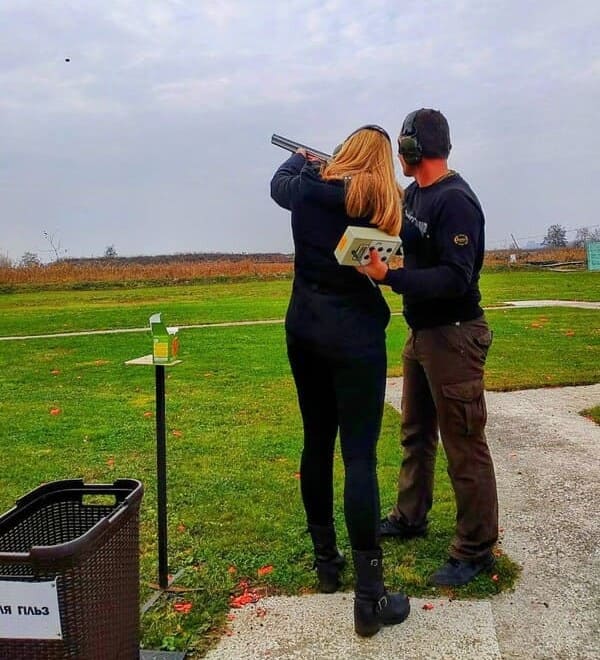 Тренування зі стрільби в тирі в Івано-Франківську — інструктор допомагає дівчині стріляти по тарілці