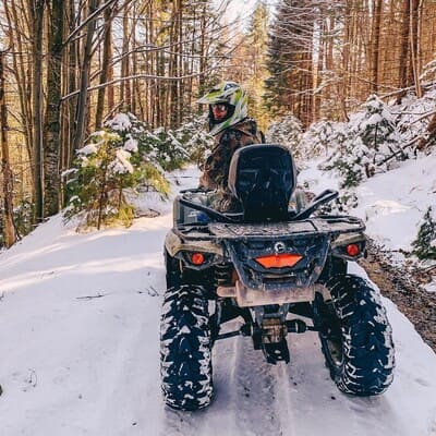 Дівчина на квадроциклі на засніженій лісовій дорозі в Яремче, зимова поїздка на квадроциклі в Карпатах