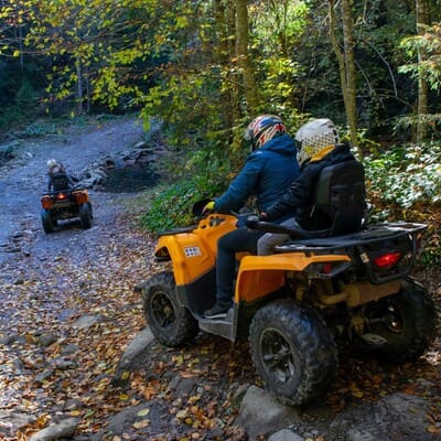 Два квадроцикла спускаються кам'яною лісовою дорогою до річки для переїзду, екстремальна поїздка на квадроциклах в Карпатах