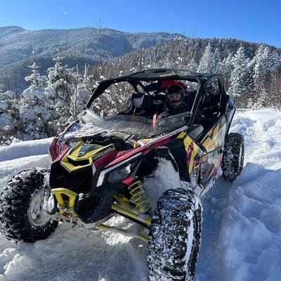 Потужний всюдихід на засніженій полонині в горах Яремчі, на фоні засніженого лісу та гірського хребта