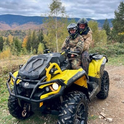 Хлопець та дівчина обіймаються на квадроциклі на гірській осінній дорозі в лісі, романтичне побачення