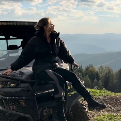 Дівчина сидить на капоті багі на карпатській полонині, насолоджуючись сонячним весняним ранком