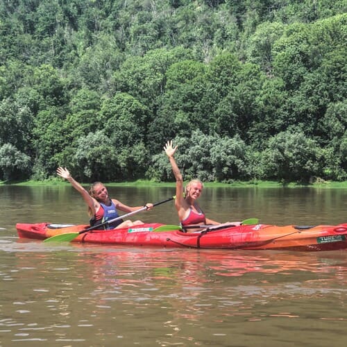 Дві дівчини у каяку на Дністрі махають рукою