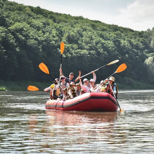 Група дорослих та дітей на рафті піднімають весла на Дністрі