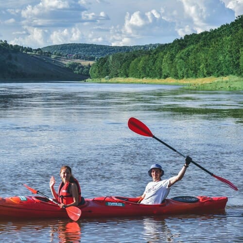 Двоє людей на каяку посеред Дністра махають у камеру — сплав по Дністру біля Івано-Франківська