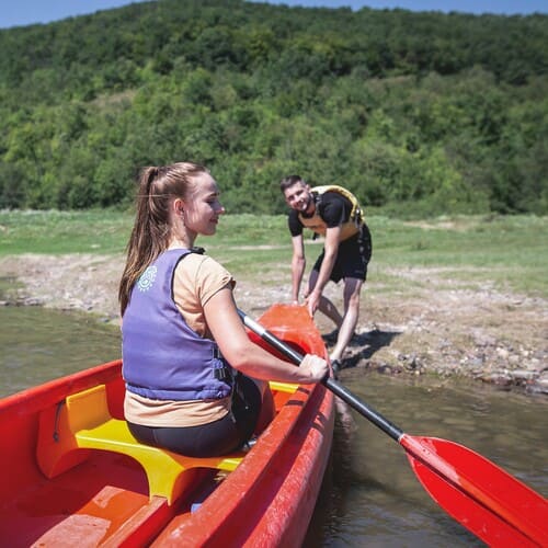 Чоловік витягує з води на берег Дністра байдарку з дівчиною